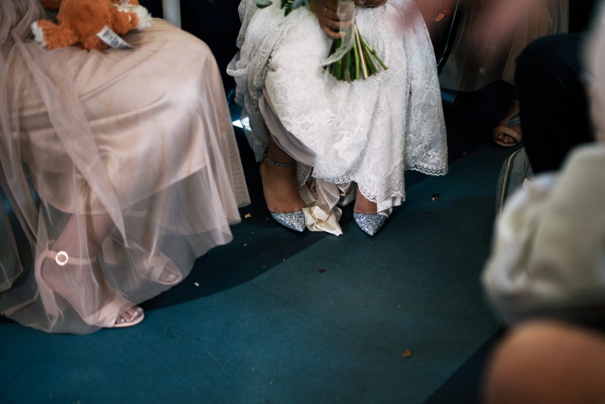 Close-up view of white wedding dress and formal attire details during ceremony.