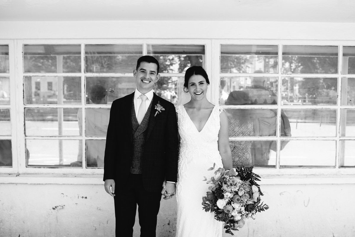 Classic black and white portrait of newlyweds with bride holding floral bouquet.