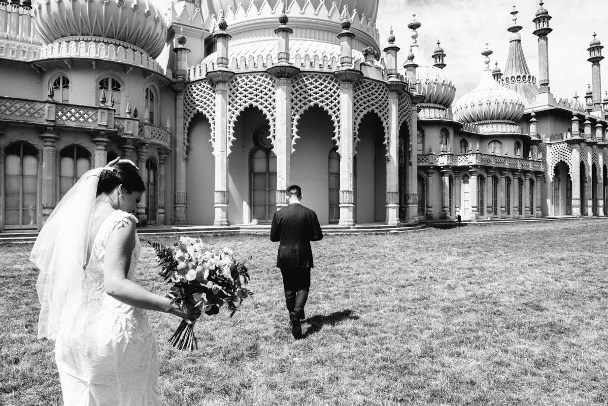 Black and white photo of couple at Brighton Pavilion with ornate domes and architecture.