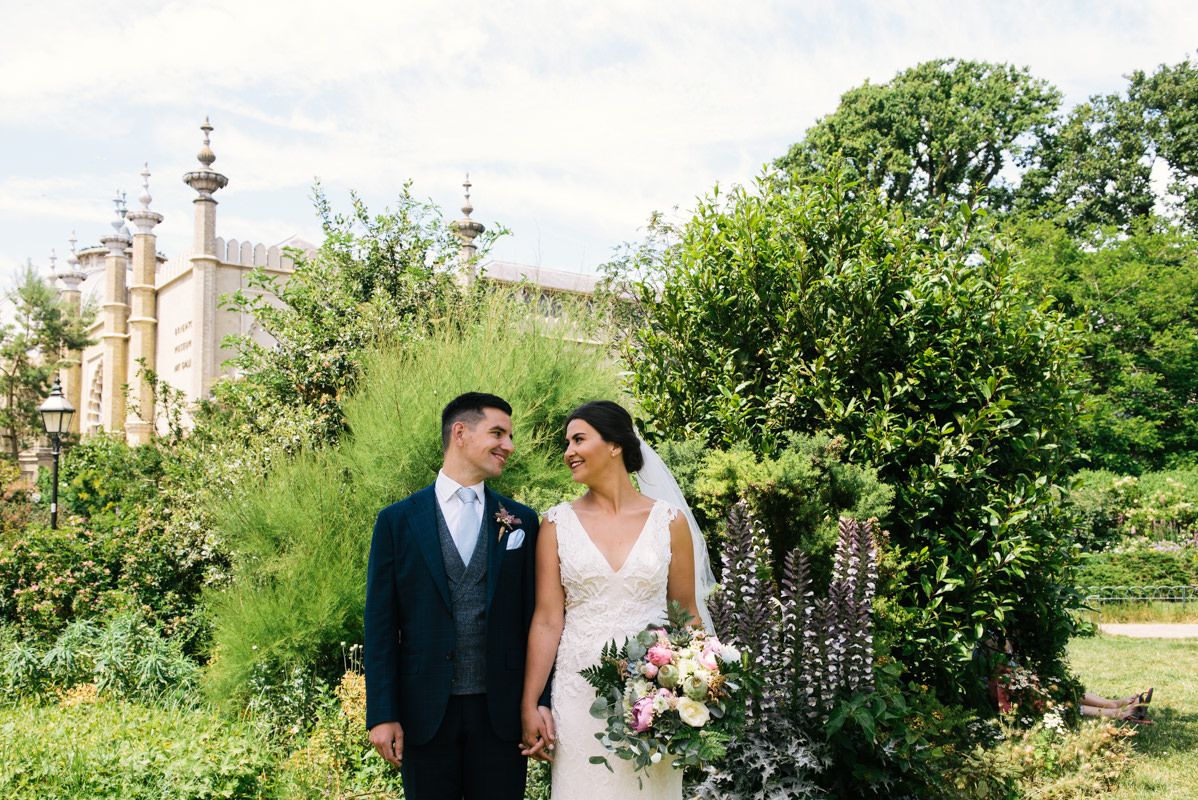A couple poses in front of ornate garden architecture on their wedding day.