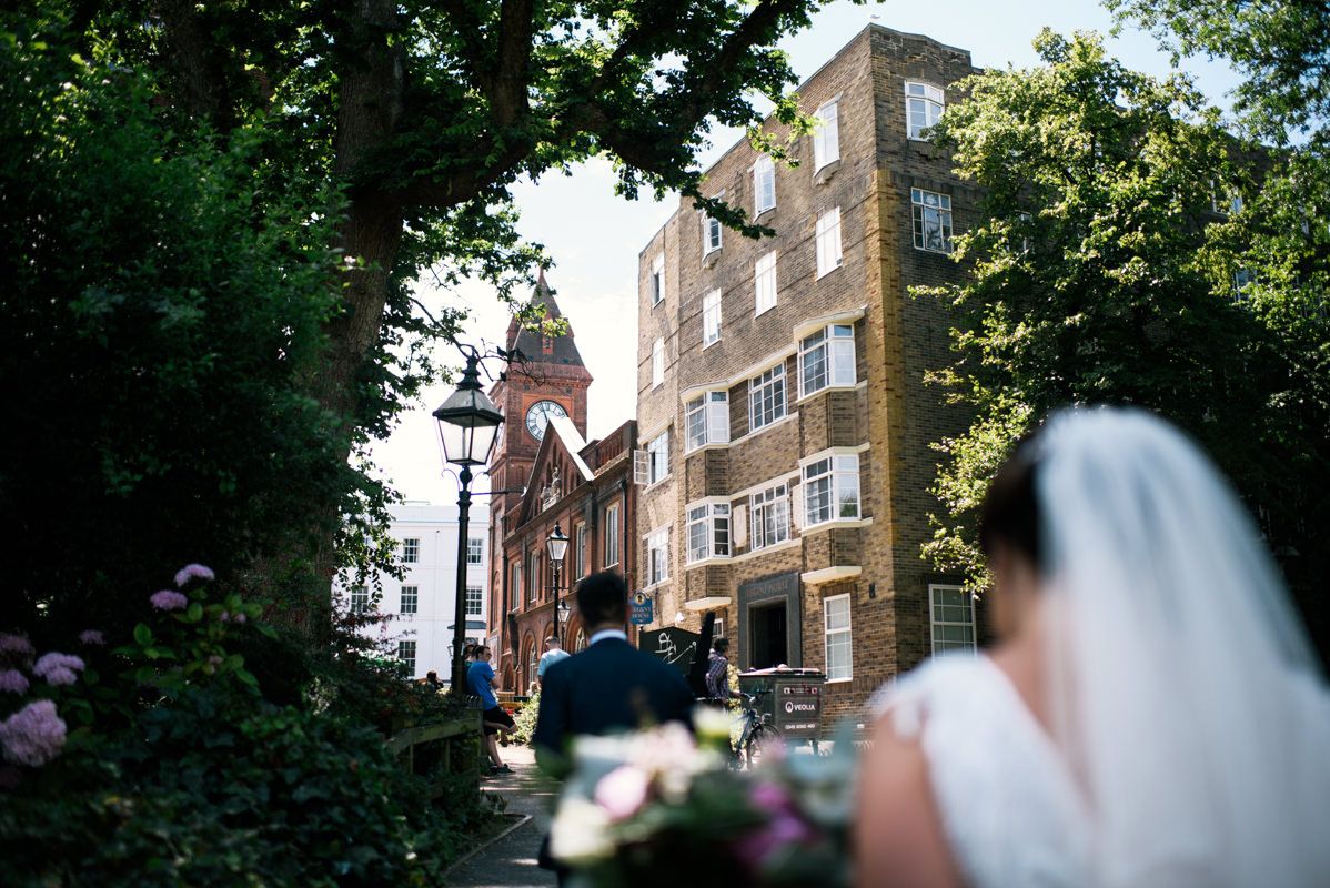 Historic brick buildings and trees frame a wedding scene in an urban setting.