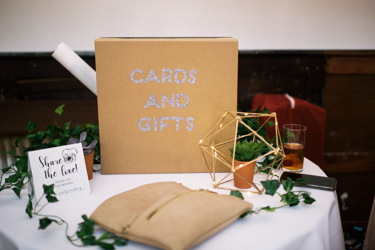 Wedding cards and gifts table with gold geometric decor and brown kraft paper box.