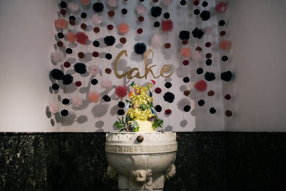 Wedding cake displayed against polka dot backdrop with 'Cake' text decoration.