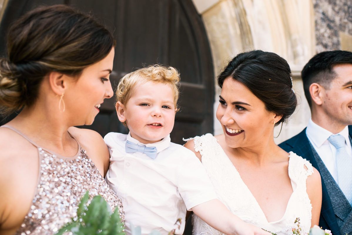 Sweet moment shared between wedding party members and young child outside church.
