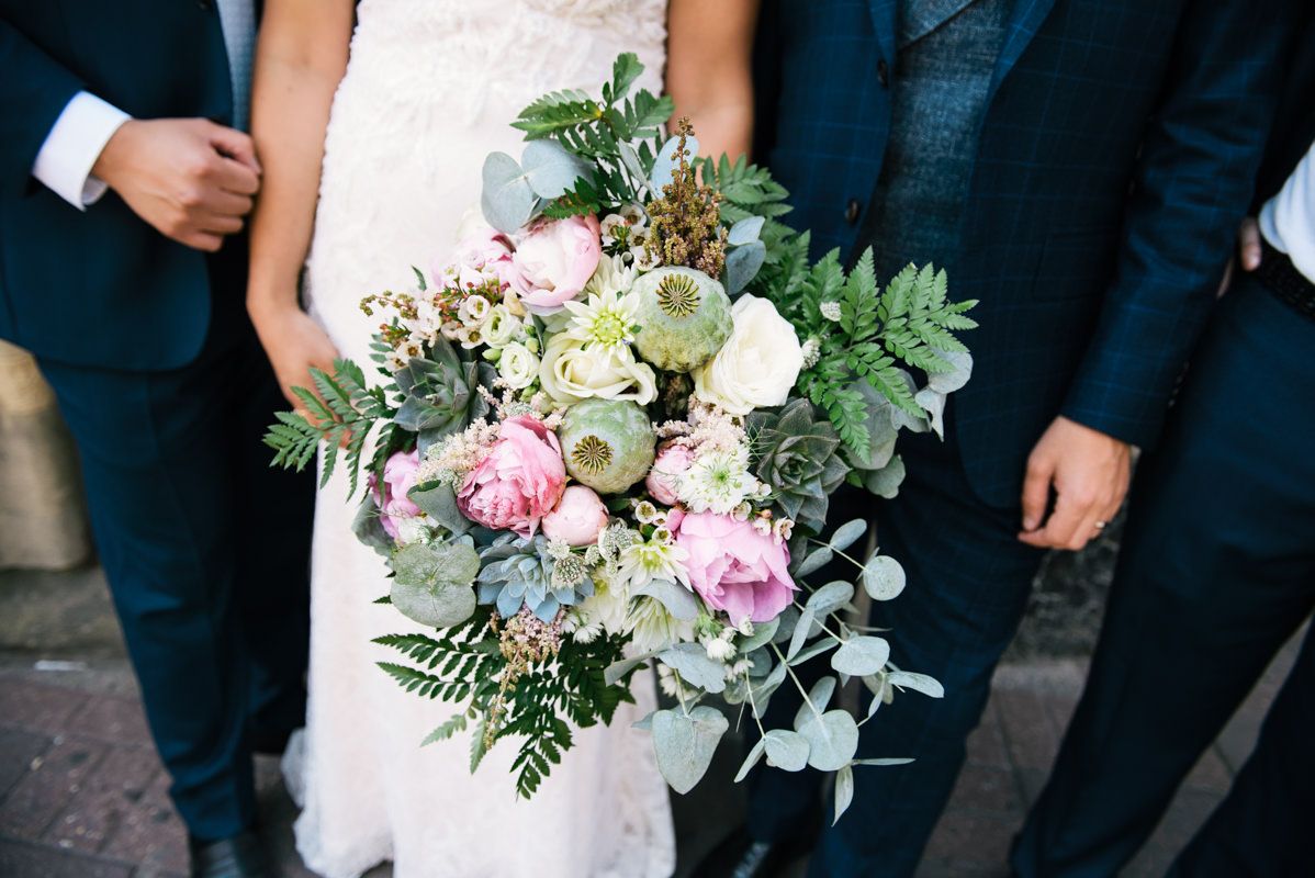 A stunning wedding bouquet featuring pink and white roses with eucalyptus and green foliage accents.