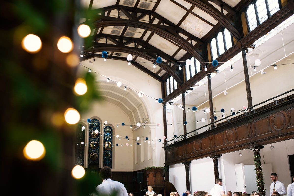 Interior view of a historic venue with exposed wooden beams and twinkling string lights.