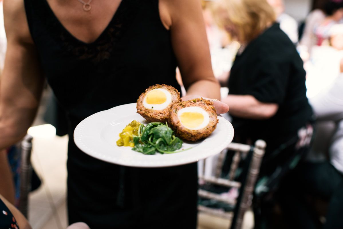 Server holding a plate of gourmet appetizers at an elegant event.