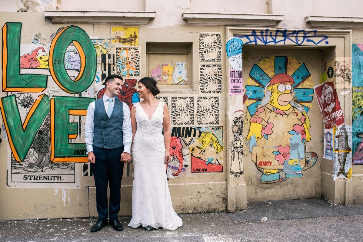 Couple poses in front of colorful street art featuring large LOVE graffiti.