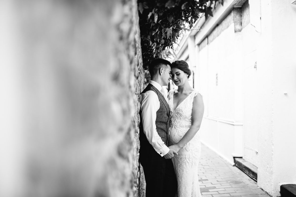 Black and white intimate wedding portrait captured between stone walls.