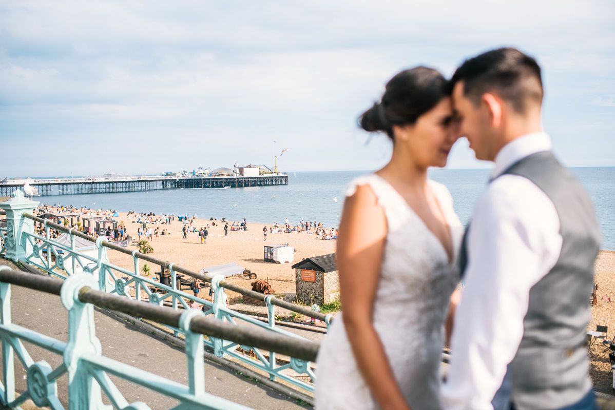 Seaside wedding portrait with Brighton Pier and beach in soft focus background.