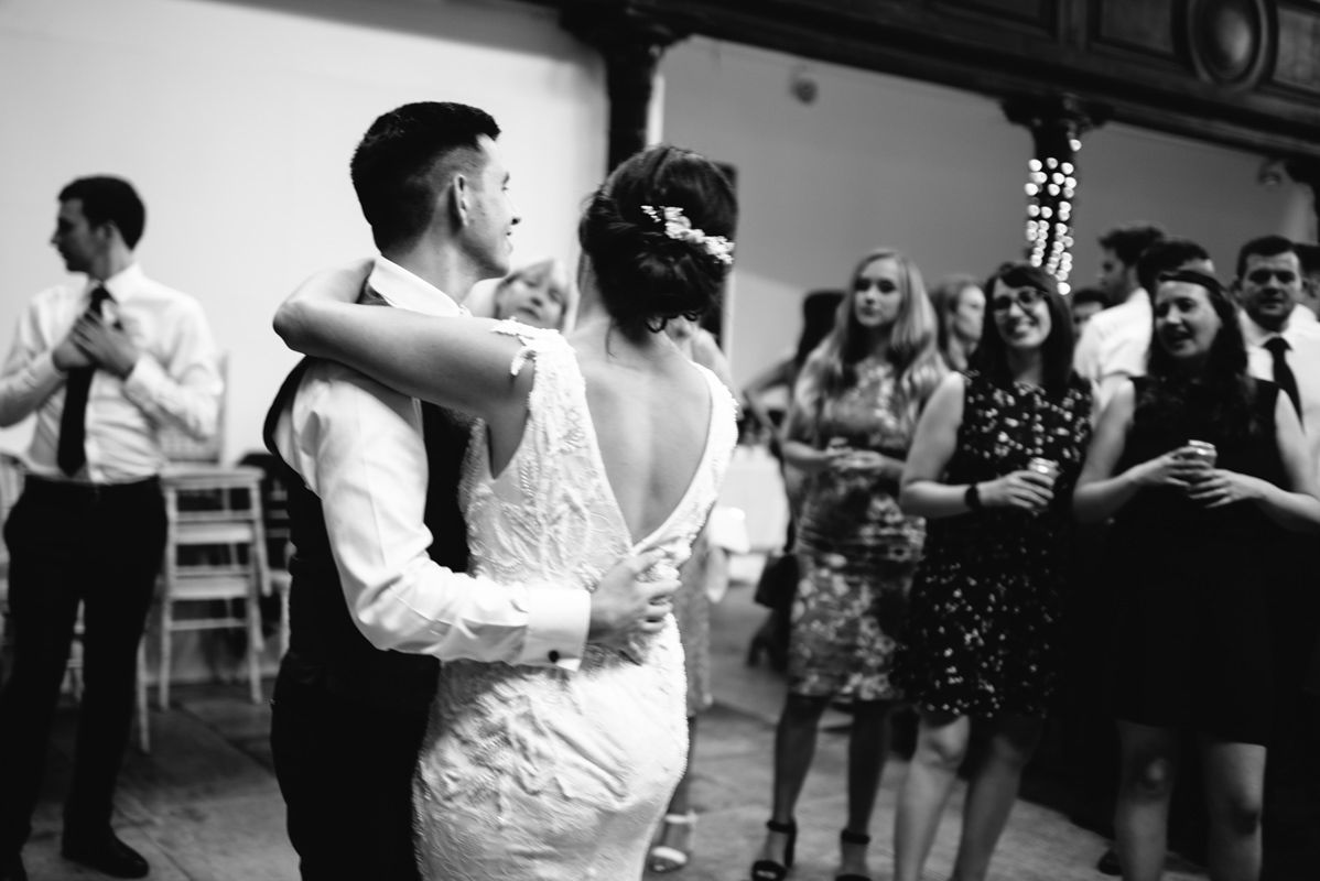 Dance floor moment at wedding reception with guests watching in background.