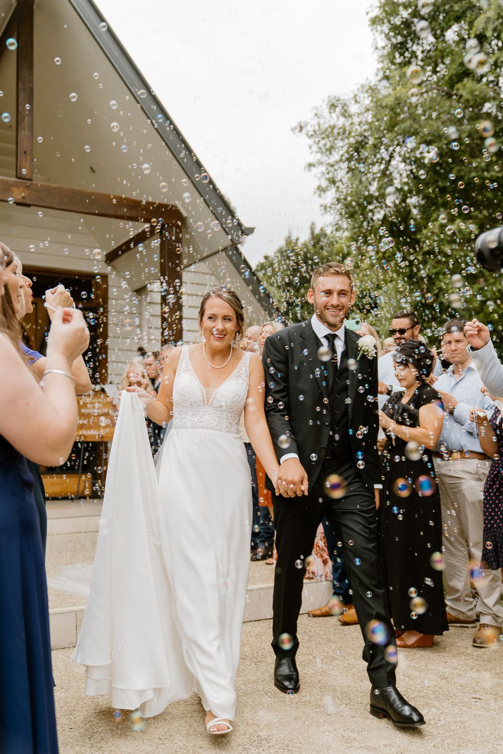 Newly married couple exiting through bubbles - by Canberra candid wedding photographer Studio Downe Weddings