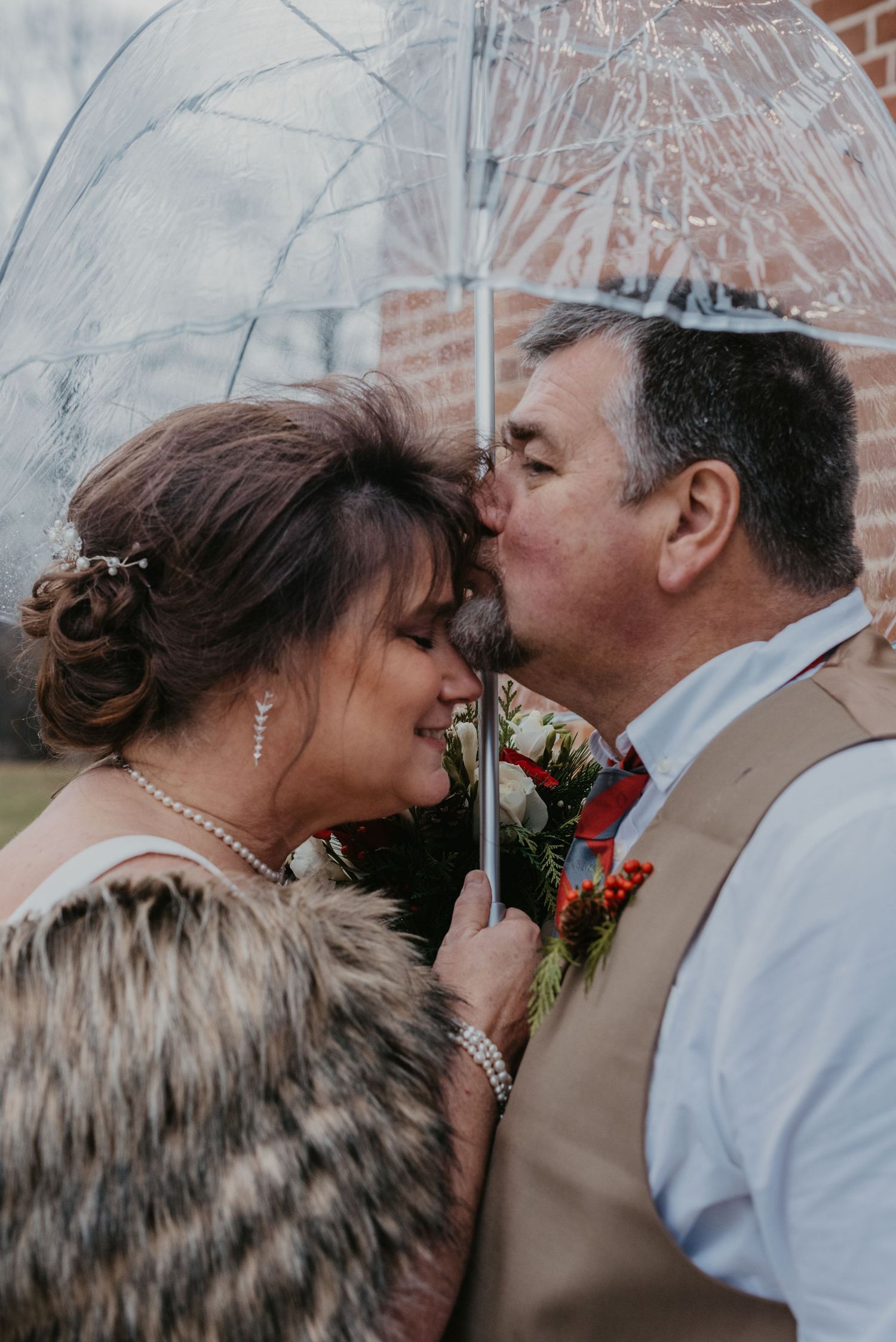 Intimate moment captured between couple against brick wall background.