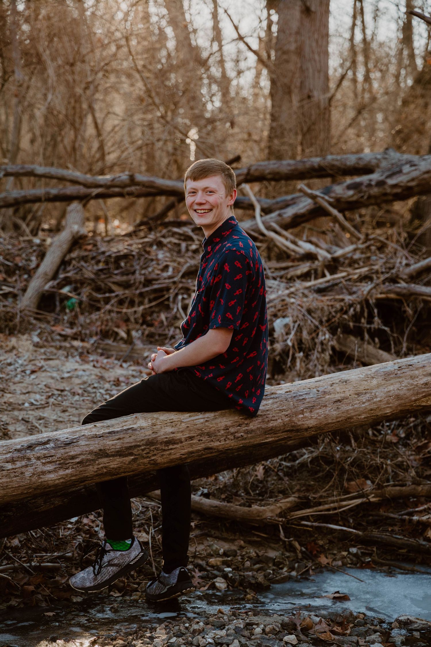 Natural outdoor photoshoot on fallen logs in a wooded setting during autumn.