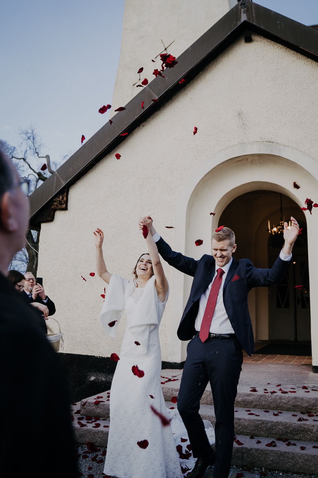 Brudpar går ut ur kyrkan till ett regn av blomblad, bröllopsfotografering Salem Stockholm