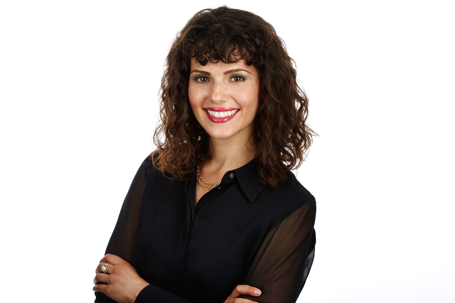 Professional headshot of a woman with curly hair in black attire against white background.