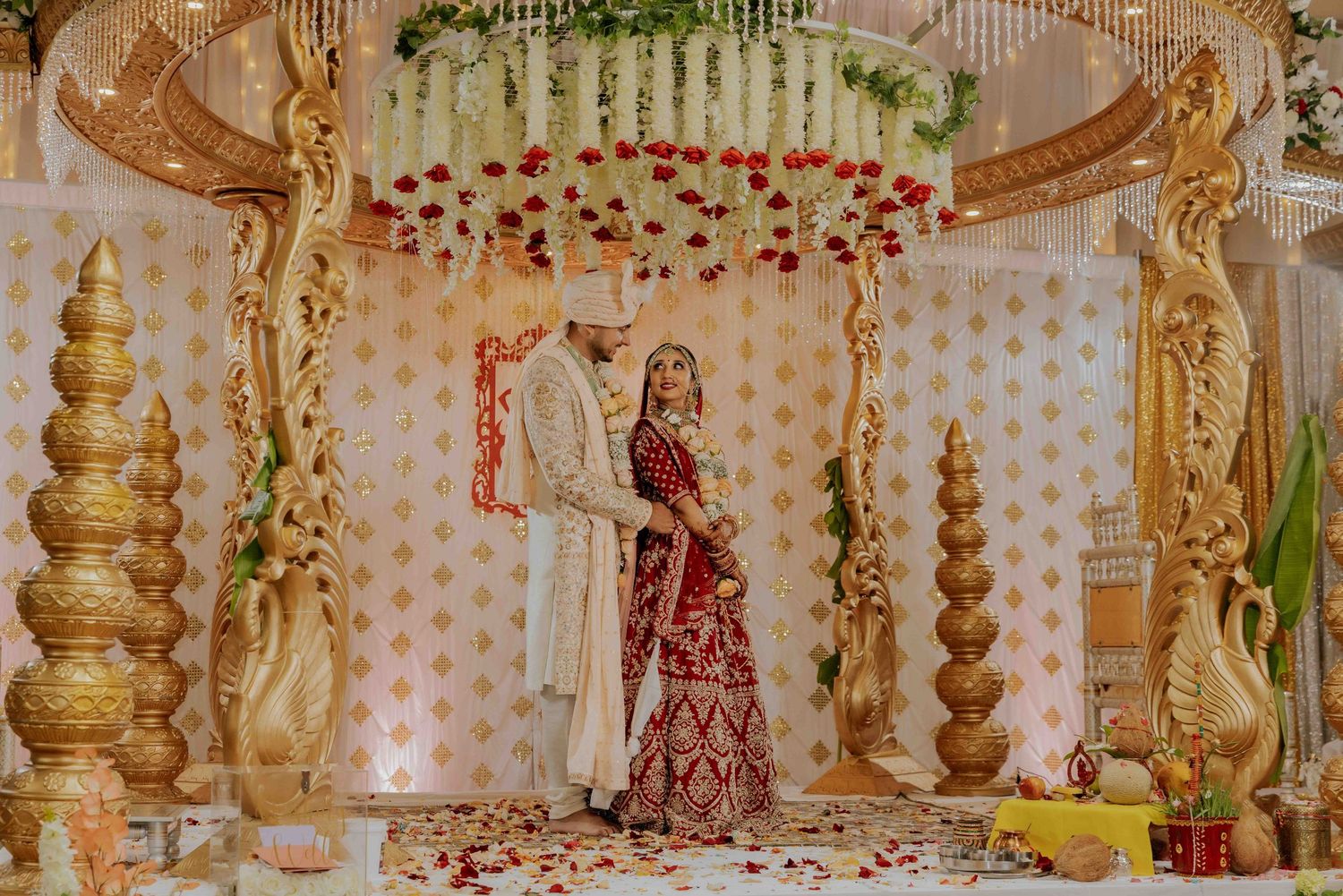 Ornate wedding mandap decorated with floral arrangements and golden accents during traditional ceremony.