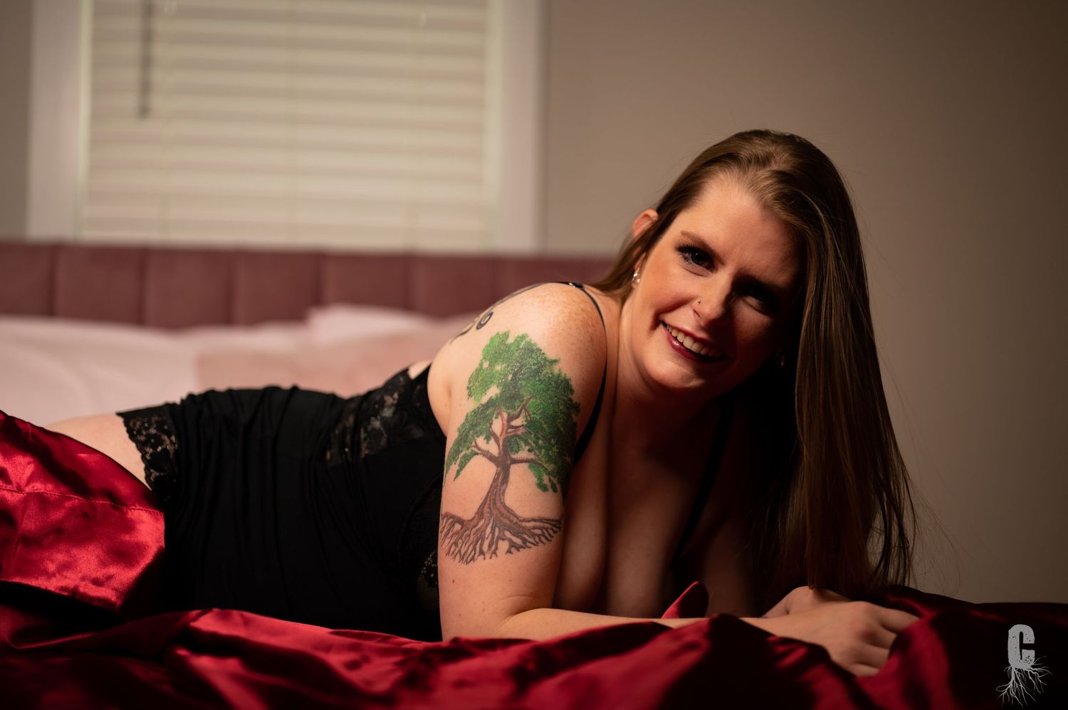 A boudoir model smiling to someone off camera during a body positive photo shoot
