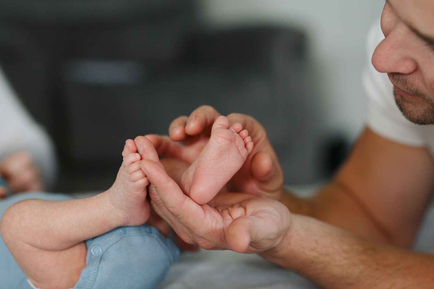 seattle newborn photographer: a father holds his newborn baby's feet at an in-home newborn photo session