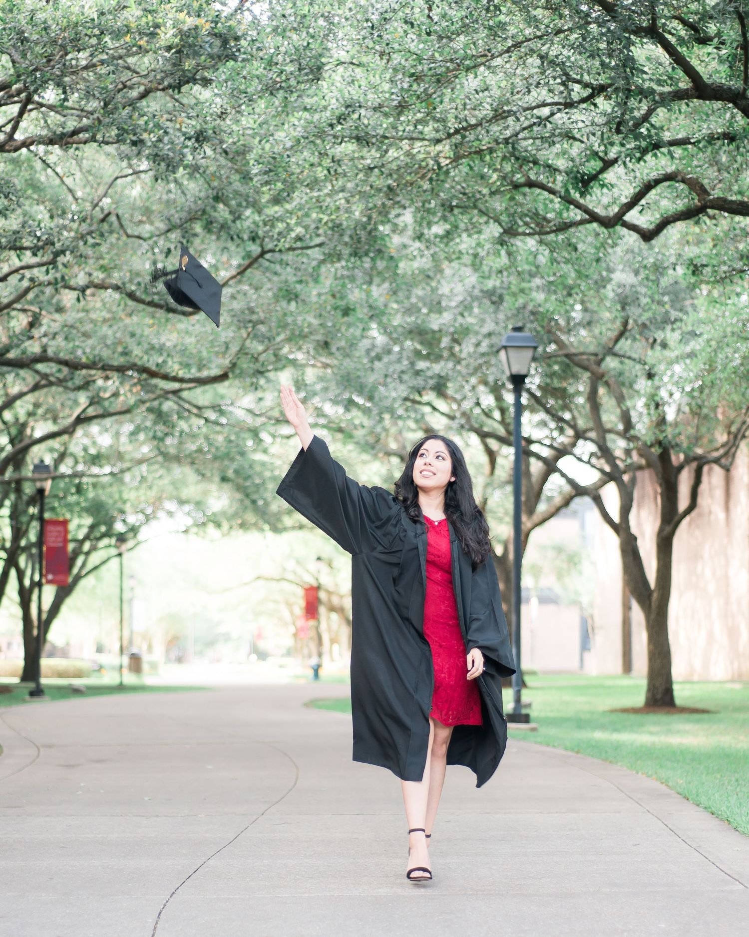 woman tossing her graduation cap at a park at University of St. Thomas in Houston, Texas