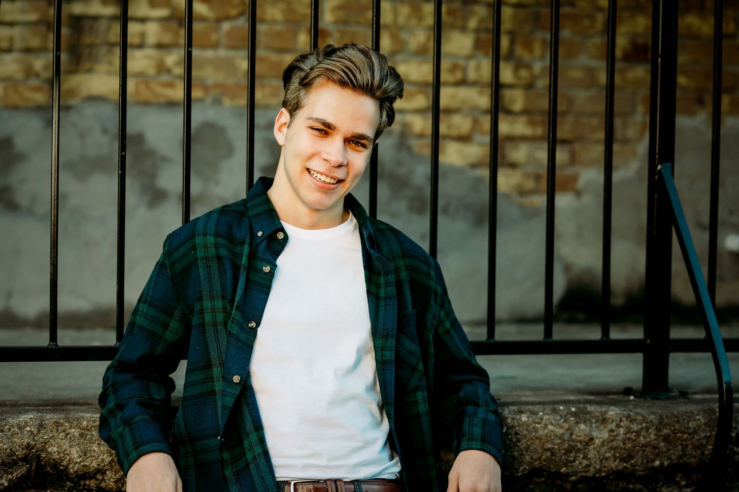 teenager boy resting against a brick wall