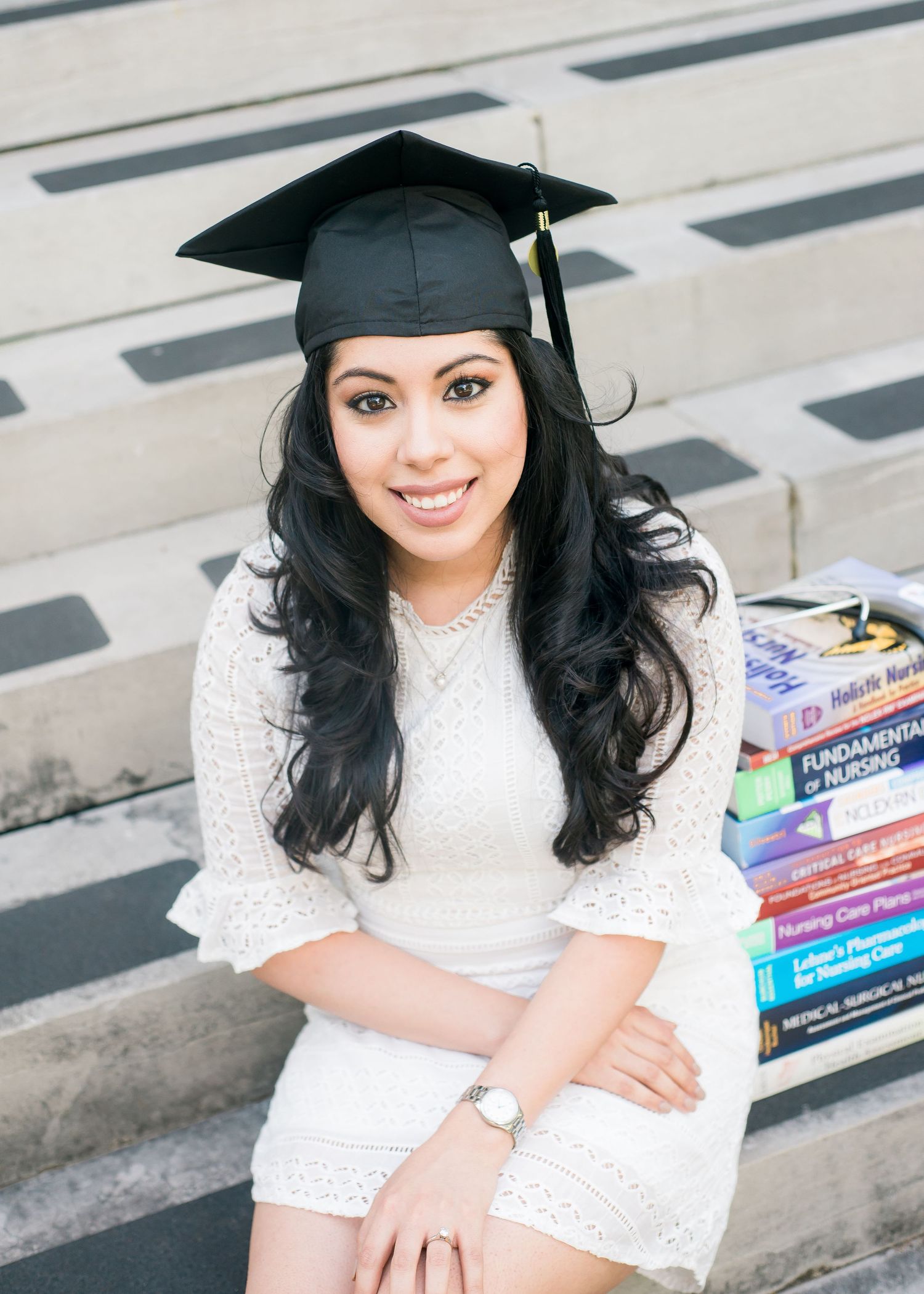 woman wearing a graduation cap with nursing books in the background  for senior portraits