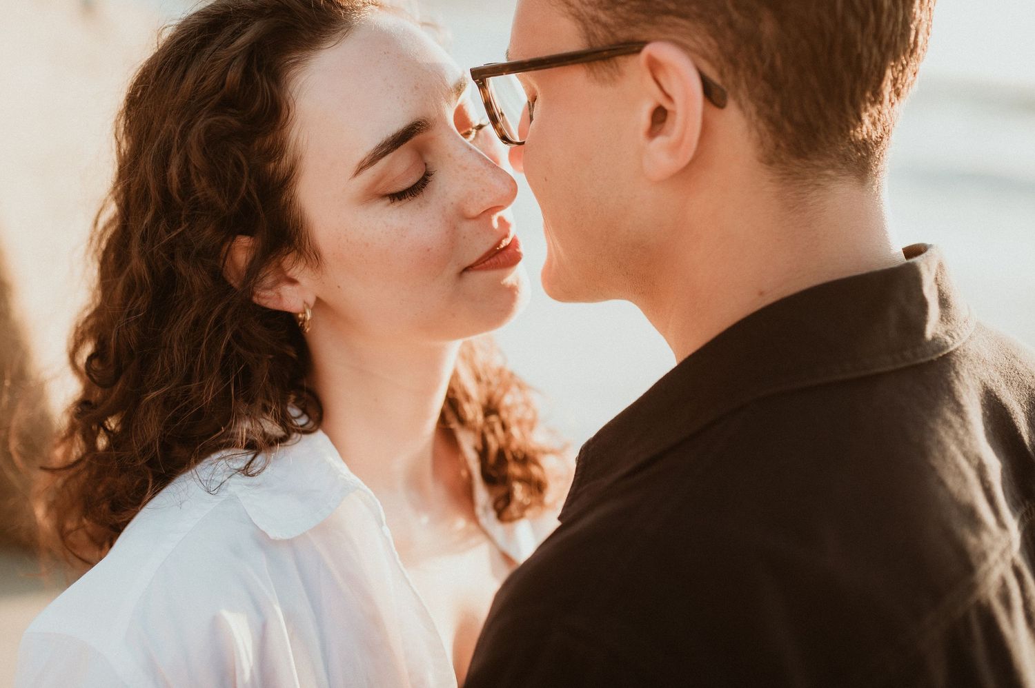 A romantic golden hour portrait of a couple about to kiss in warm sunlight.