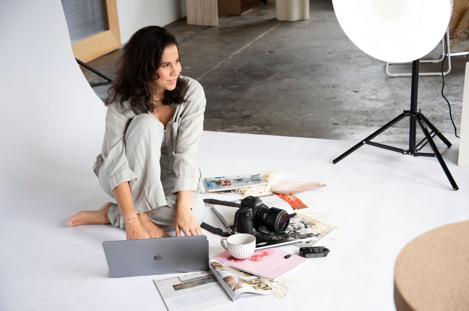 Photography studio scene with camera equipment and prints scattered on white floor.