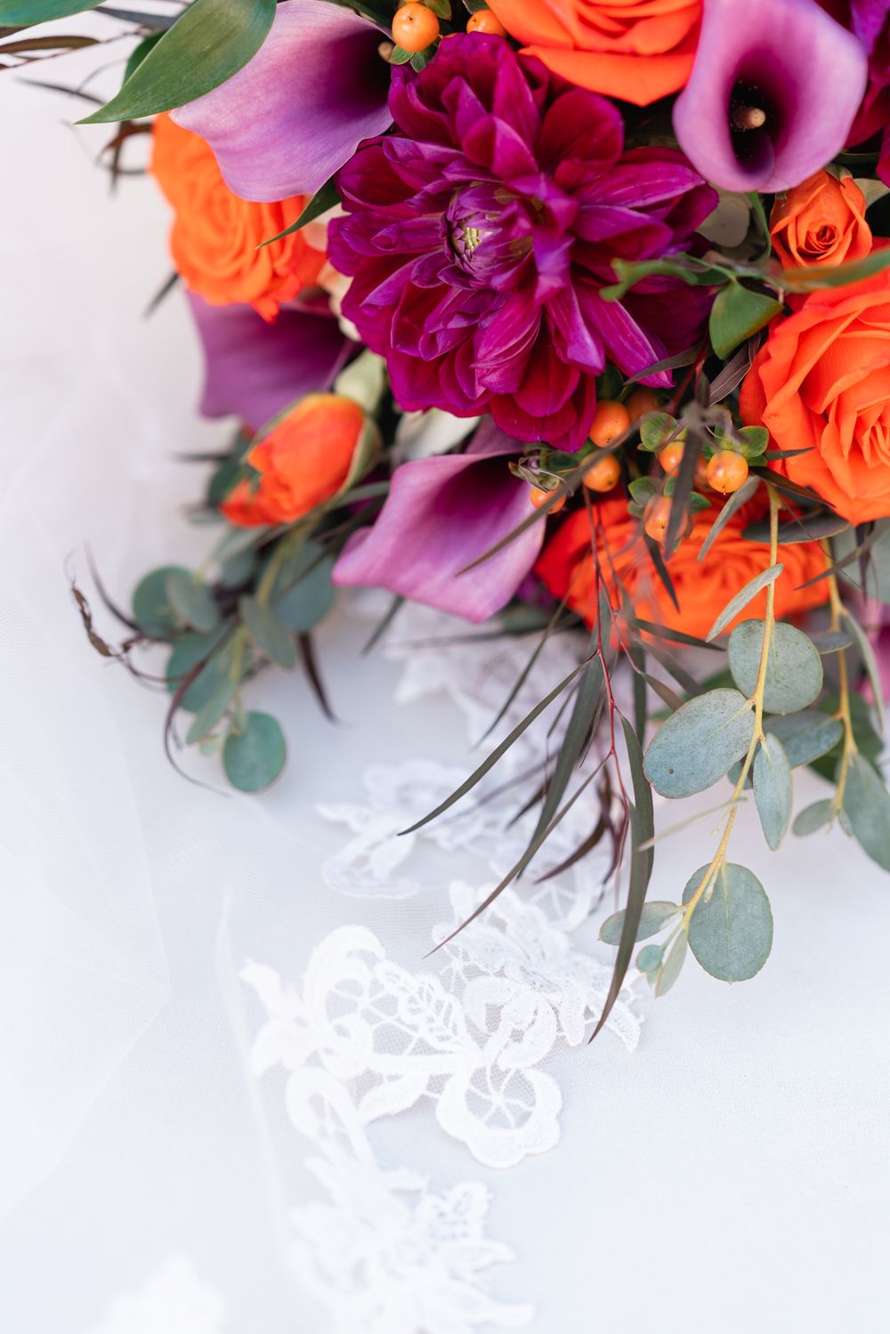 Vibrant wedding bouquet with coral roses, pink calla lilies and magenta dahlias.