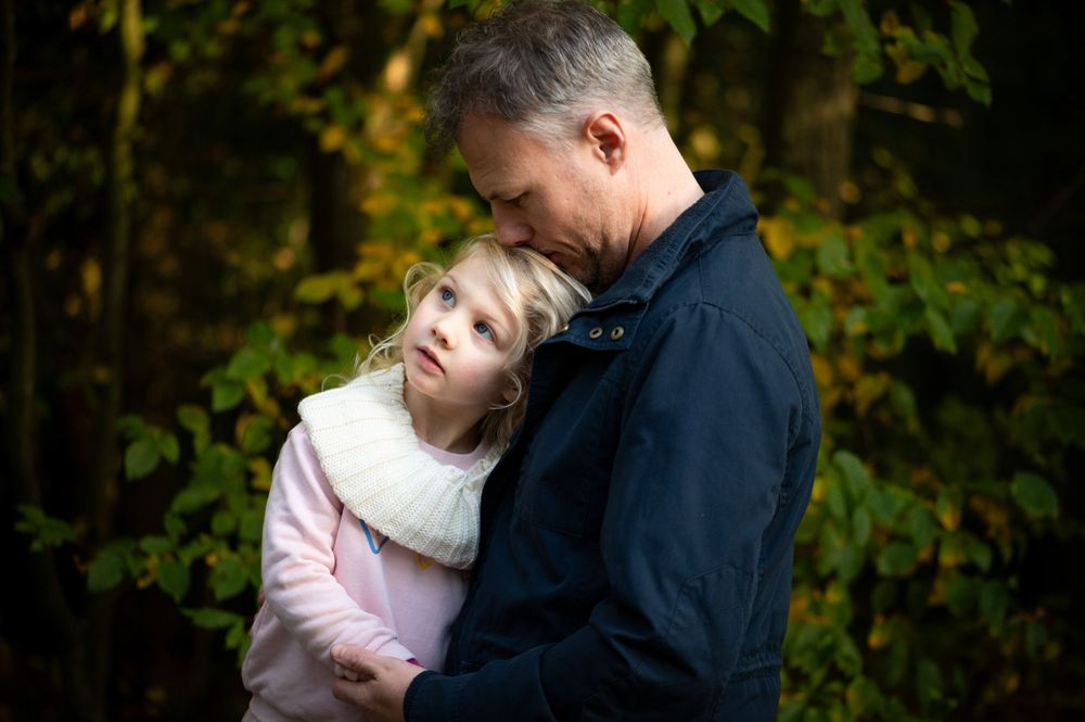 Intimate daddy and daughter moment snuggled up during a walk to the woods.