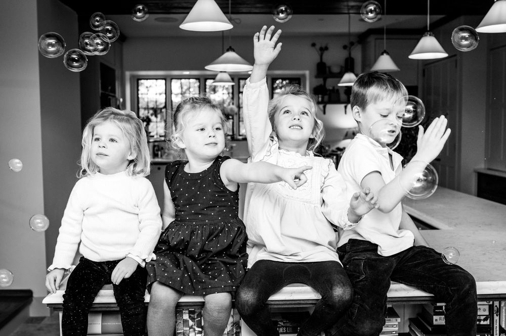 4 children sitting on the breakfast bar popping bubbles during family photoshoot in Ashtead