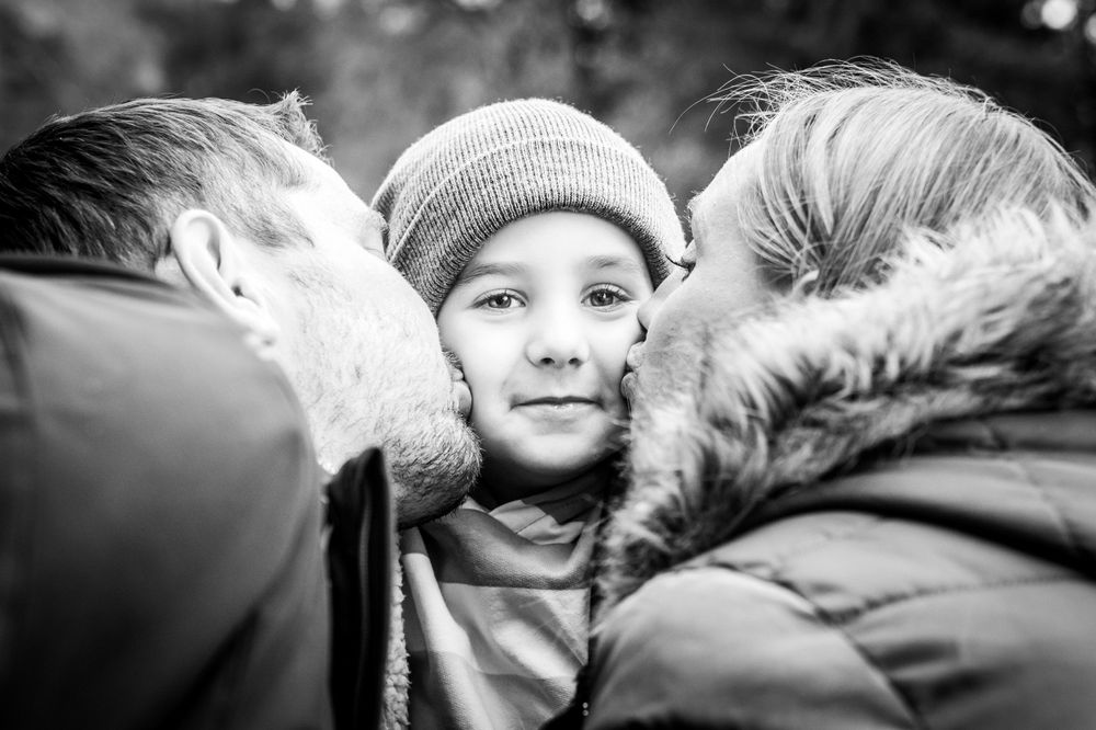 Mummy and Daddy kissing their little boy on the cheeks during family photoshoot, Surrey