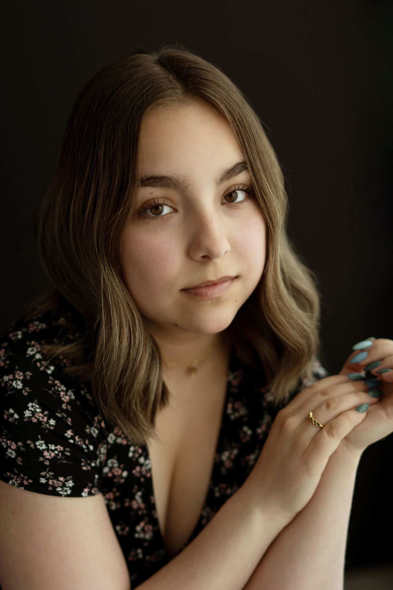 Moody portrait in floral dress with soft lighting and natural makeup.