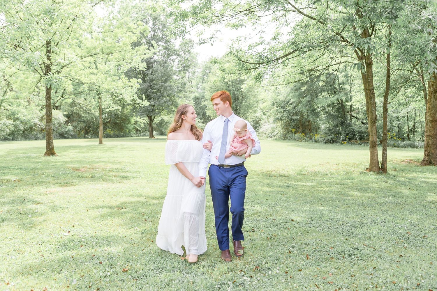 couple with baby walking in woods, baby photoshoot sarasota, family photographer northport fl, newborn photo session lakewood ranch, venice