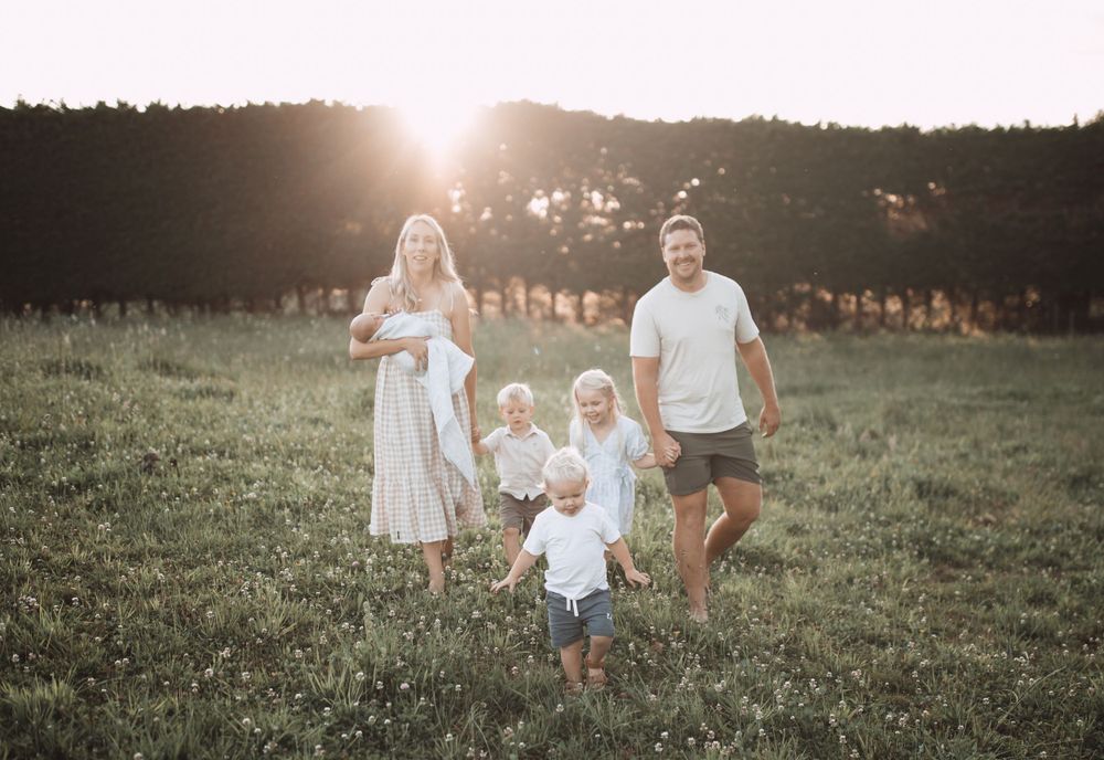 Family enjoying a casual stroll through a grassy meadow at golden hour.