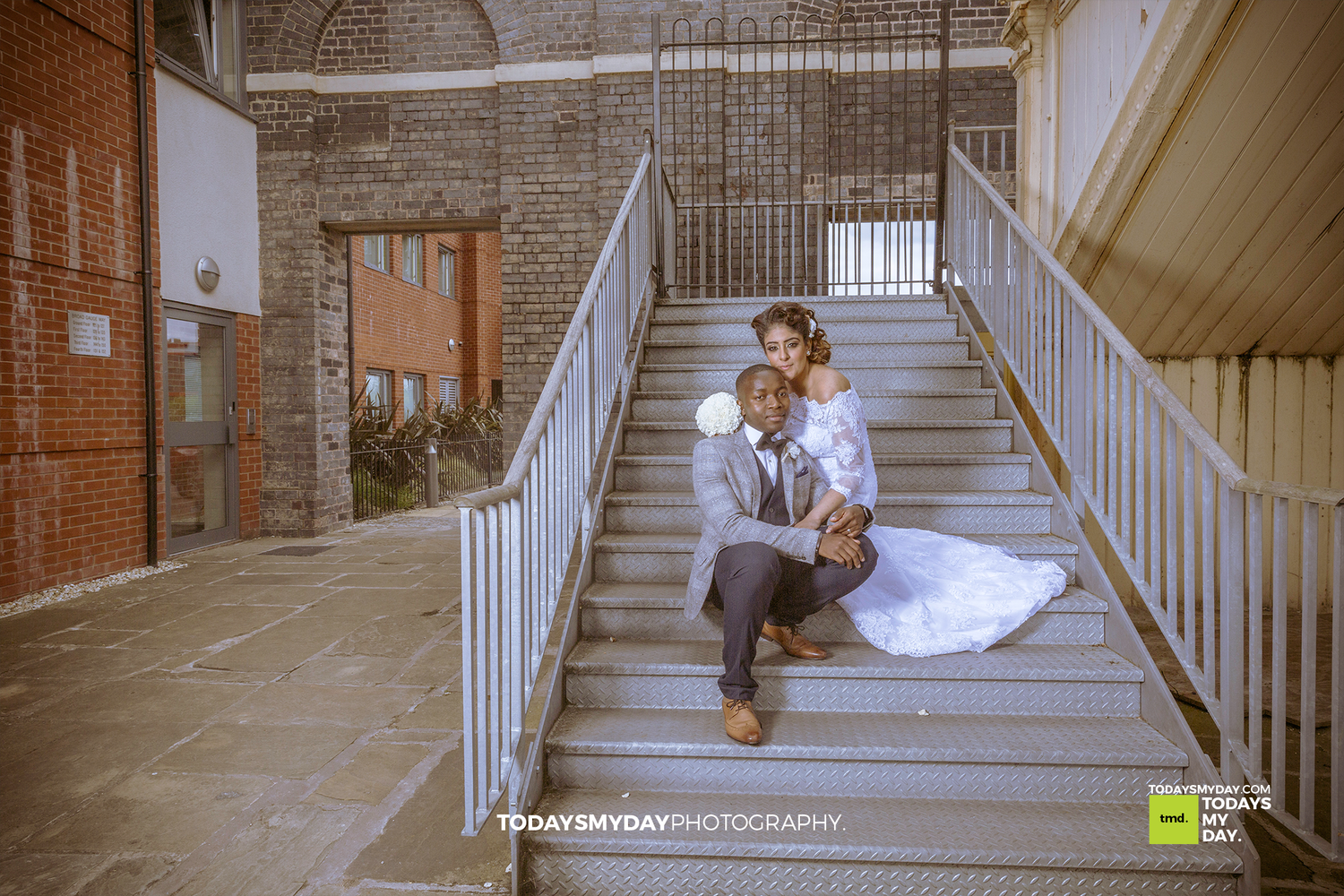 Wedding photo on industrial staircase with exposed brick and metal railings.