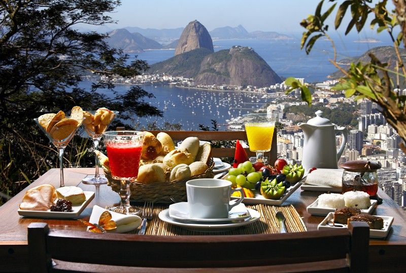 Breakfast spread with coffee, juice, and pastries overlooking Sugarloaf Mountain and Rio de Janeiro bay in Brazil.