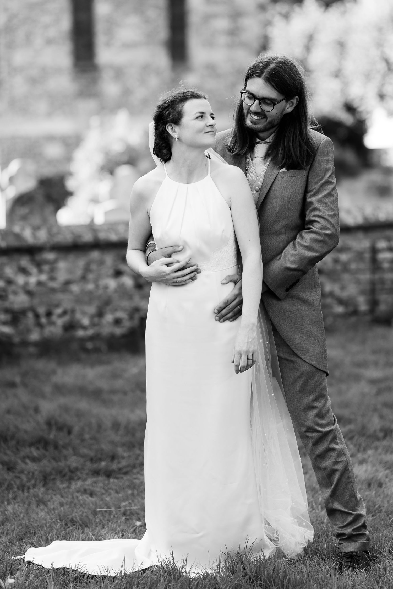 Intimate black and white wedding portrait of couple against stone wall background.