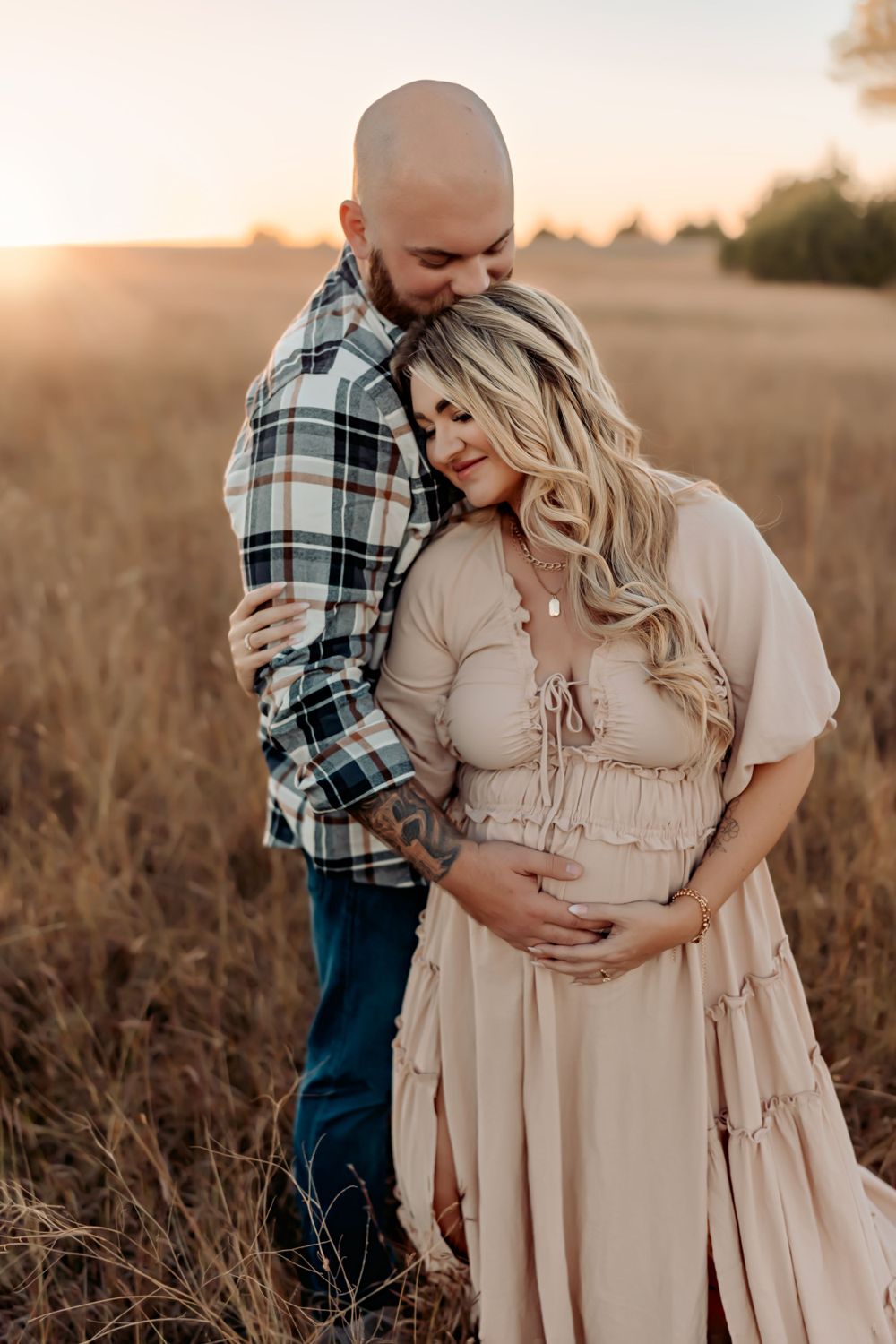 An intimate maternity portrait at sunset in a wheat field.