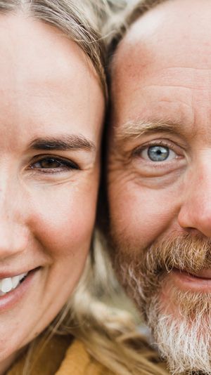 Close up portrait showing half of two smiling faces side by side against a blurred background.
