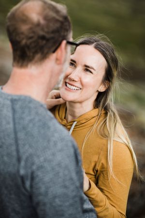 A couple shares a tender moment while standing on a mountainside trail.