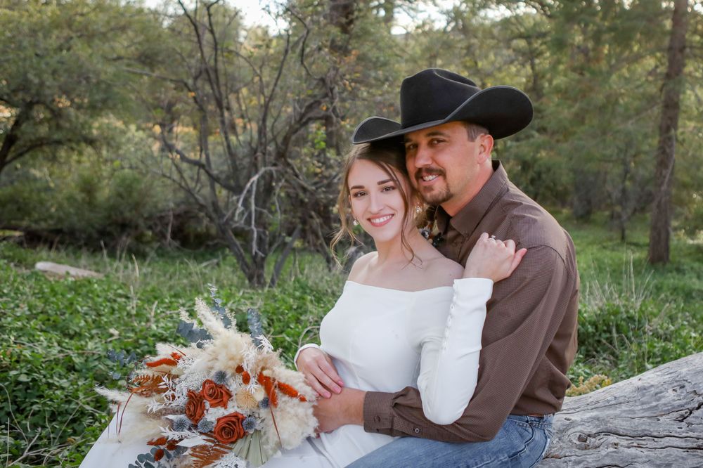 Portrait of a bride and groom sitting on a wooden log in the forest