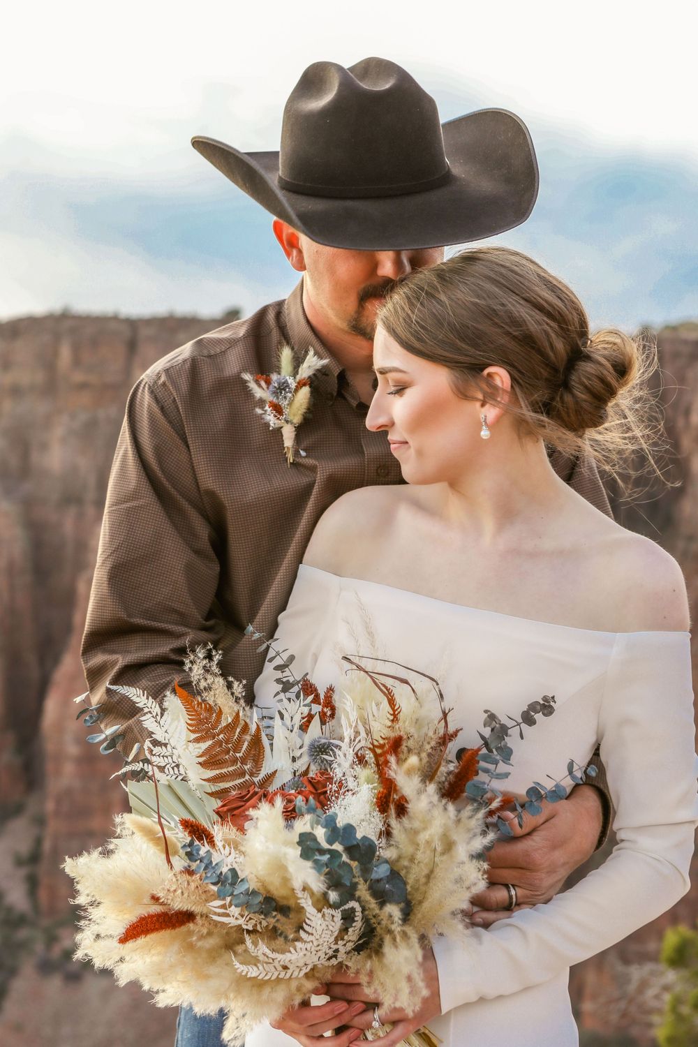 Portrait of a groom standing behind his wife, kissing the side of her head