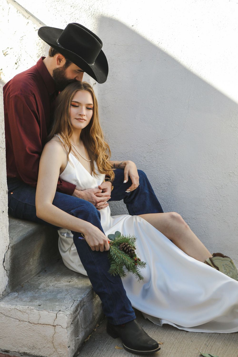 Portrait of a groom sitting on the stairs, his wife between his legs on the step below