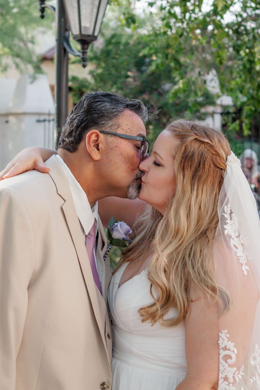 Portrait of a bride and groom kissing in front of greenery