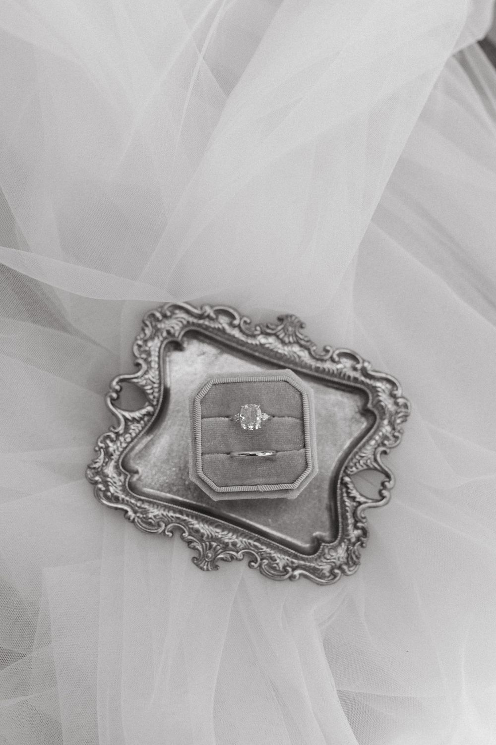 Diamond ring nestled in an antique silver ring box surrounded by flowing tulle fabric.