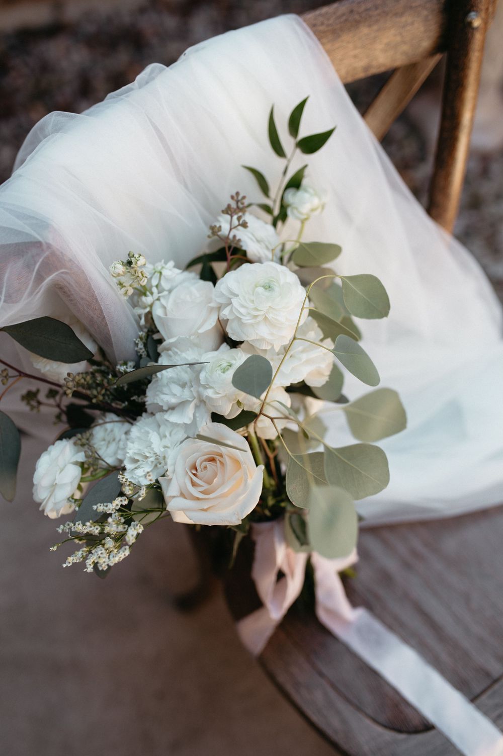 Elegant white rose wedding bouquet with eucalyptus leaves and delicate baby's breath flowers.