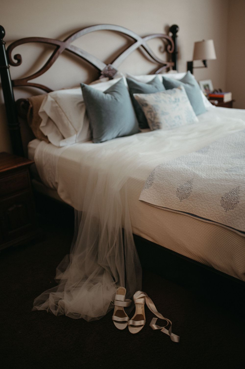 Elegant bedroom setup with flowing white veil and bridal sandals beside the bed.