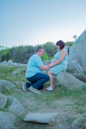 Tender moment between couple on rocky terrain during sunset photo session.
