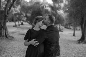 A romantic black and white photo of a couple sharing an intimate moment in a grove.